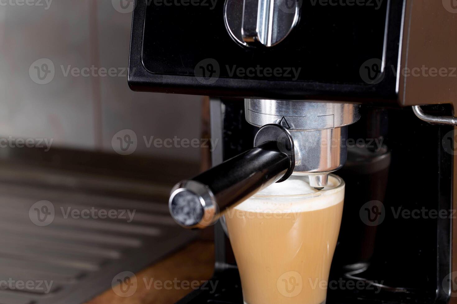 Making coffee with cappuccino milk in a cappuccino machine with a manual cappuccino maker on the background of a wooden table top. Close-up photo