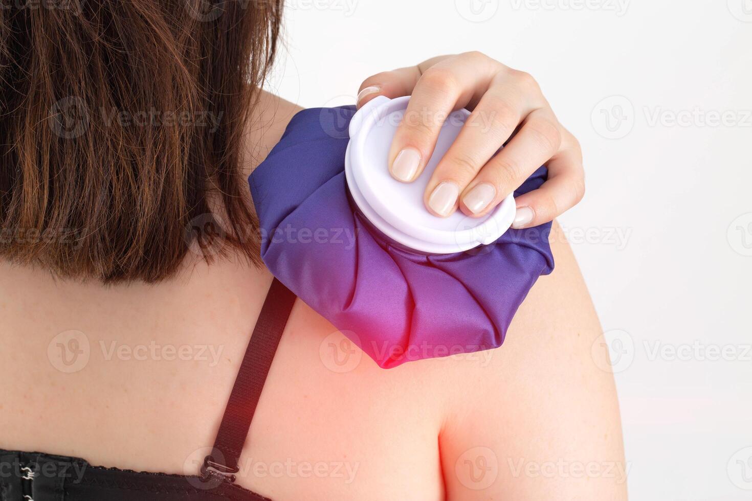 A girl holds a medical ice bag on her shoulder joint for bruising and swelling to reduce bruising. Cold treatment photo