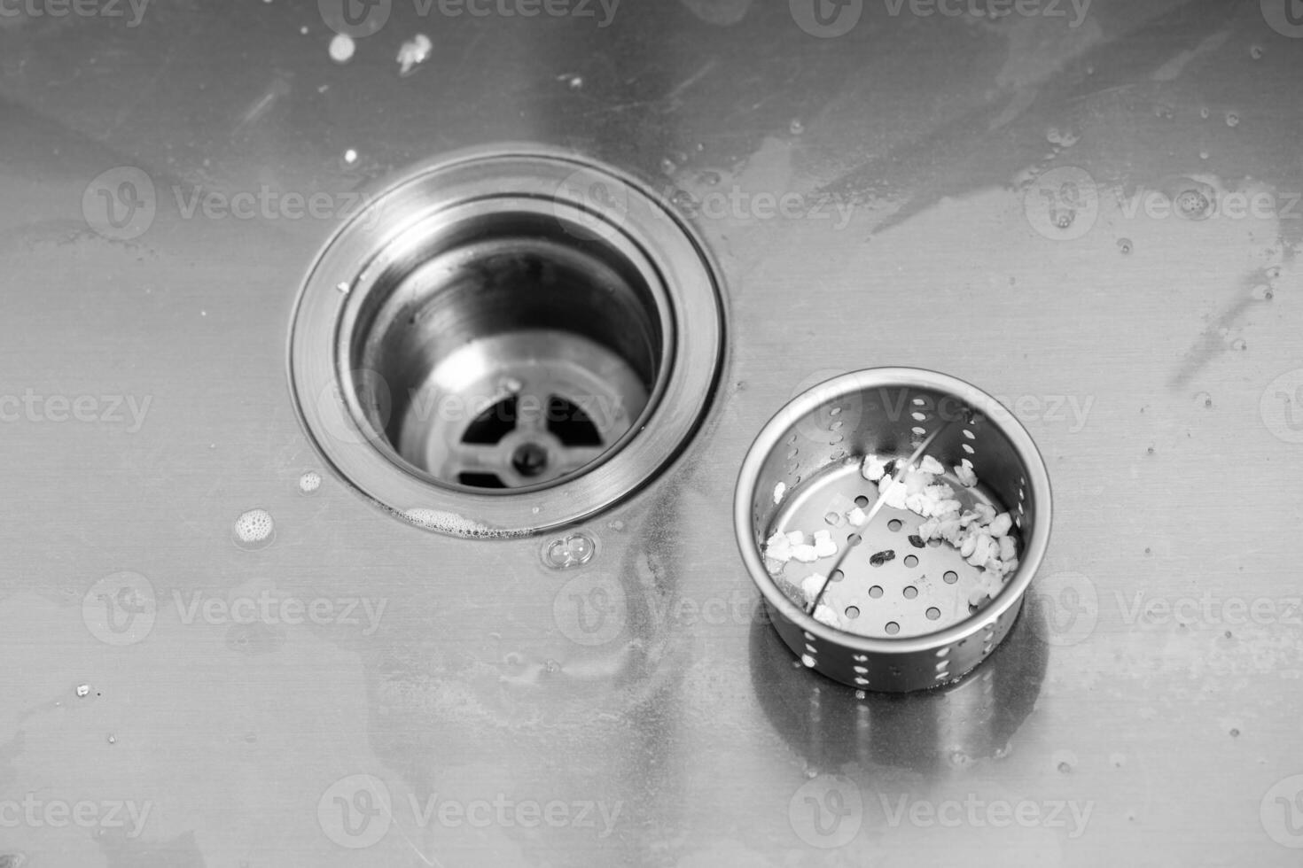Protective mesh filter in a metal sink in the kitchen from blockage. Clogged sink with food particles after washing dishes. Copy space for text photo