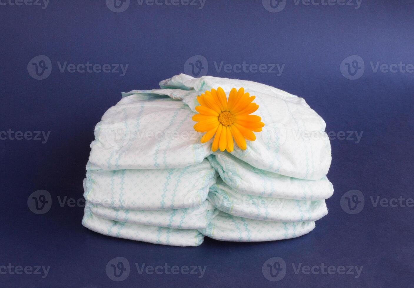 Baby diapers on a blue background and an orange flower on diapers photo