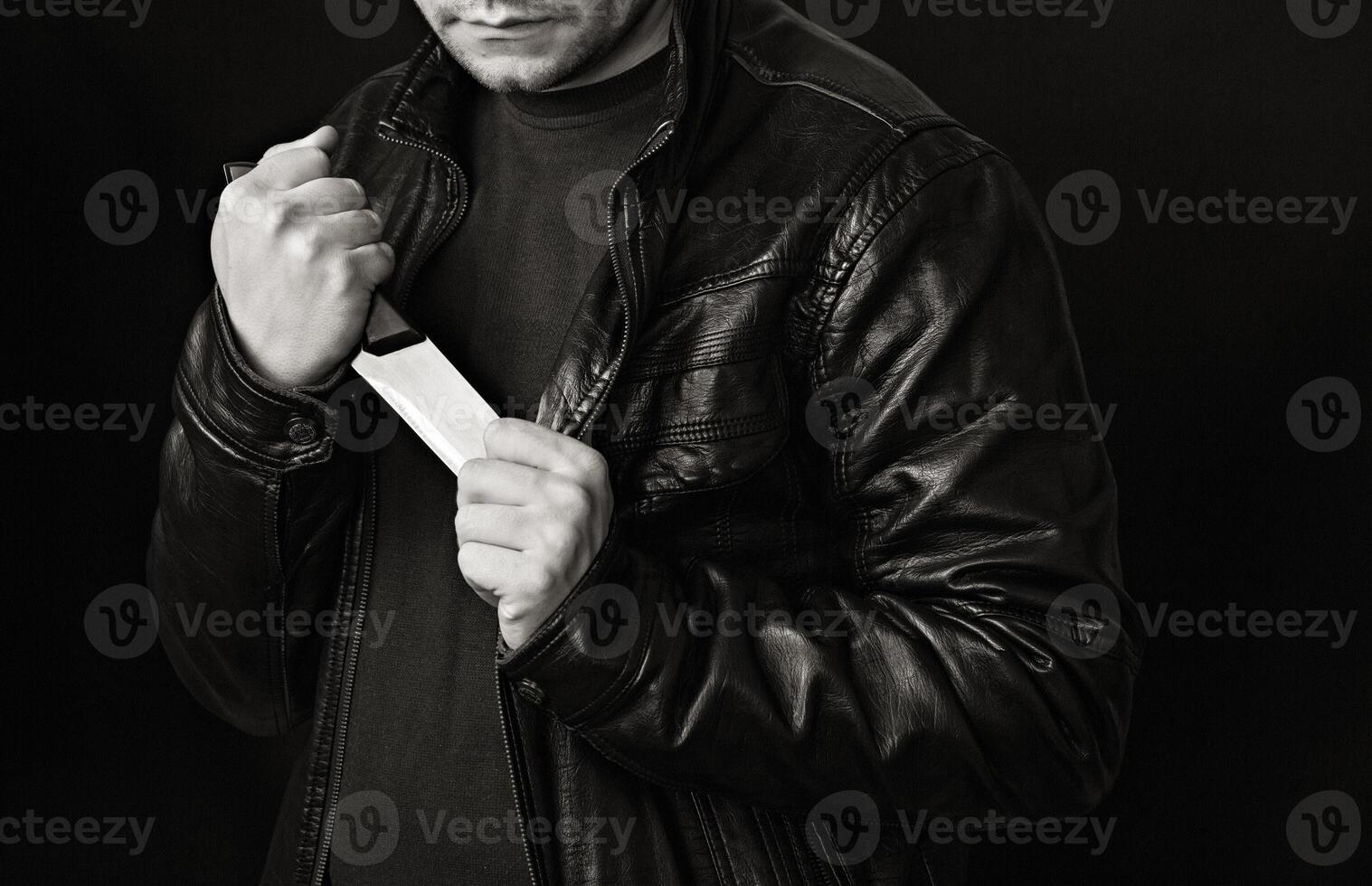 A man takes a knife out of a jacket, a black background, black and white photo