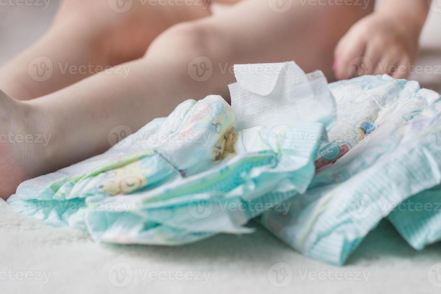 Baby diapers and a small child sitting next to him, close-up photo