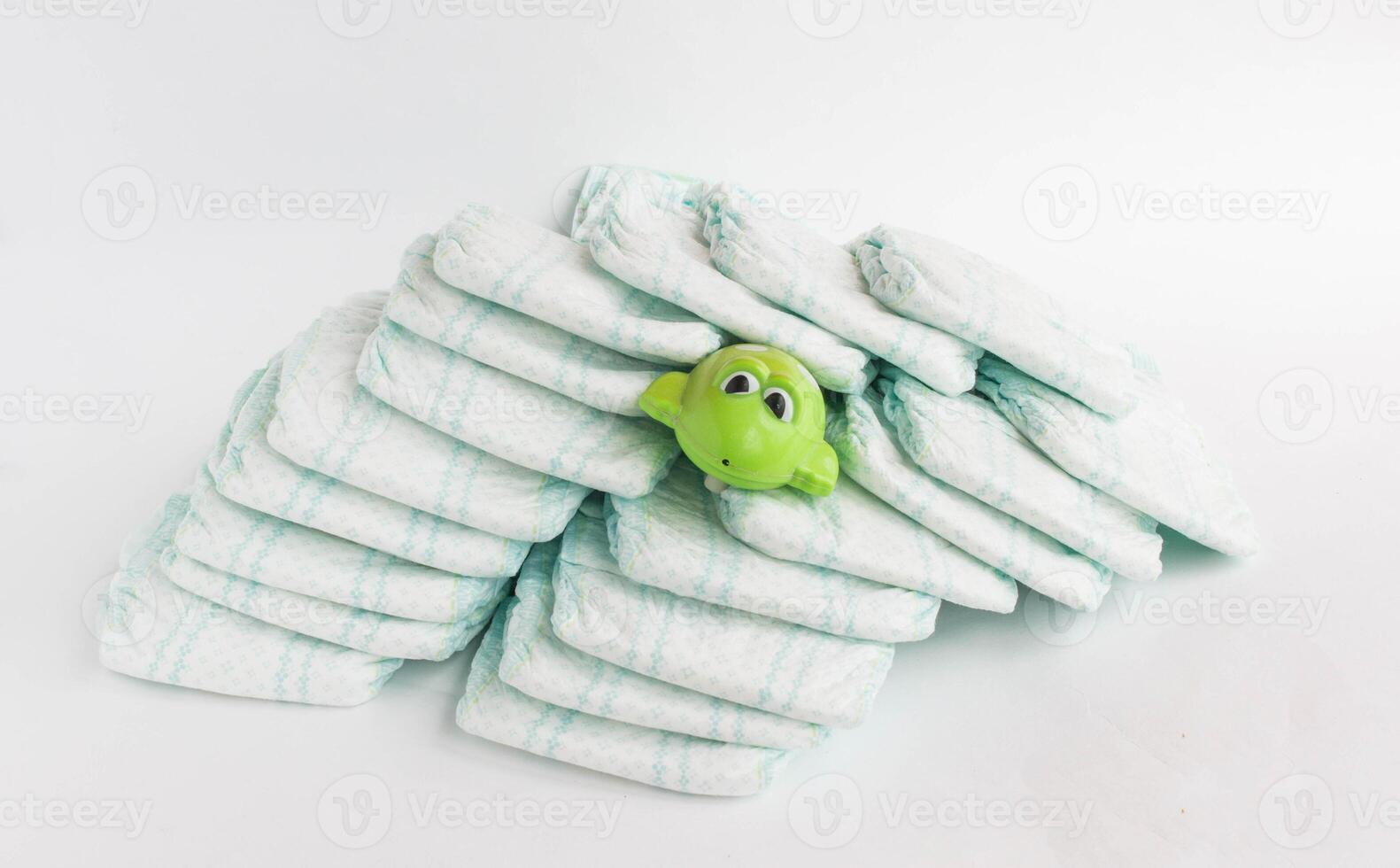 Baby diapers on a white background and a children's toy frog photo