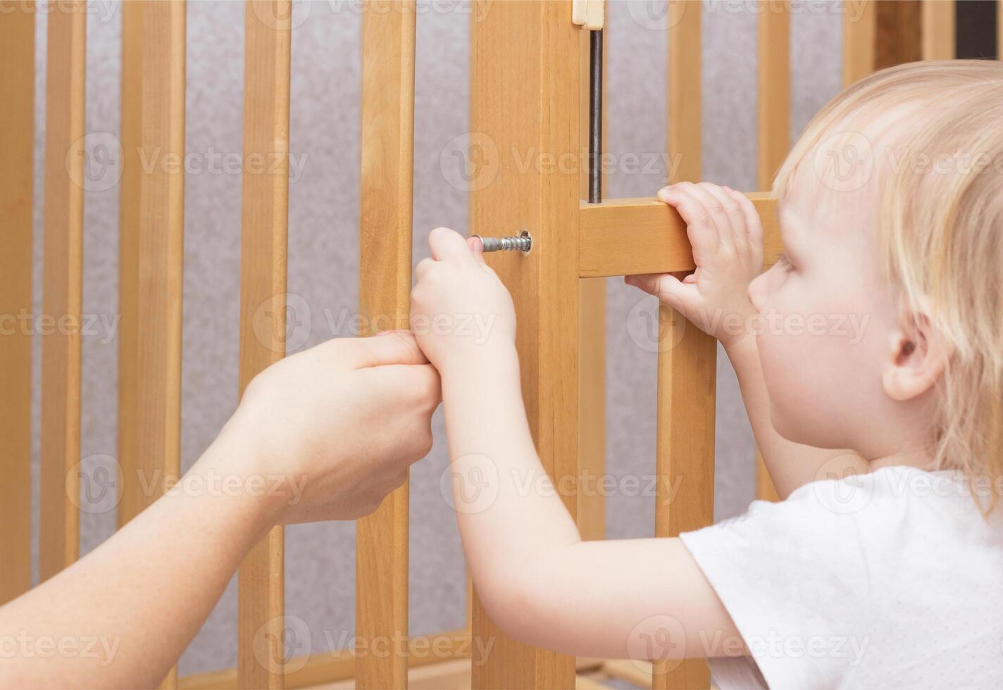 Mother and child are assembling a crib, close-up, caucasian, interior photo