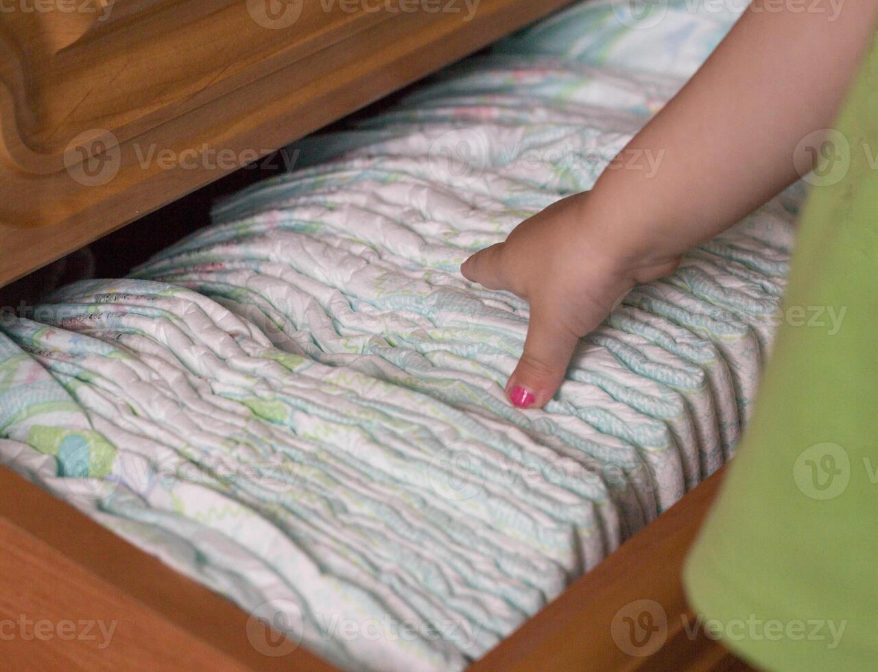 child's hand takes out diapers, close-up photo