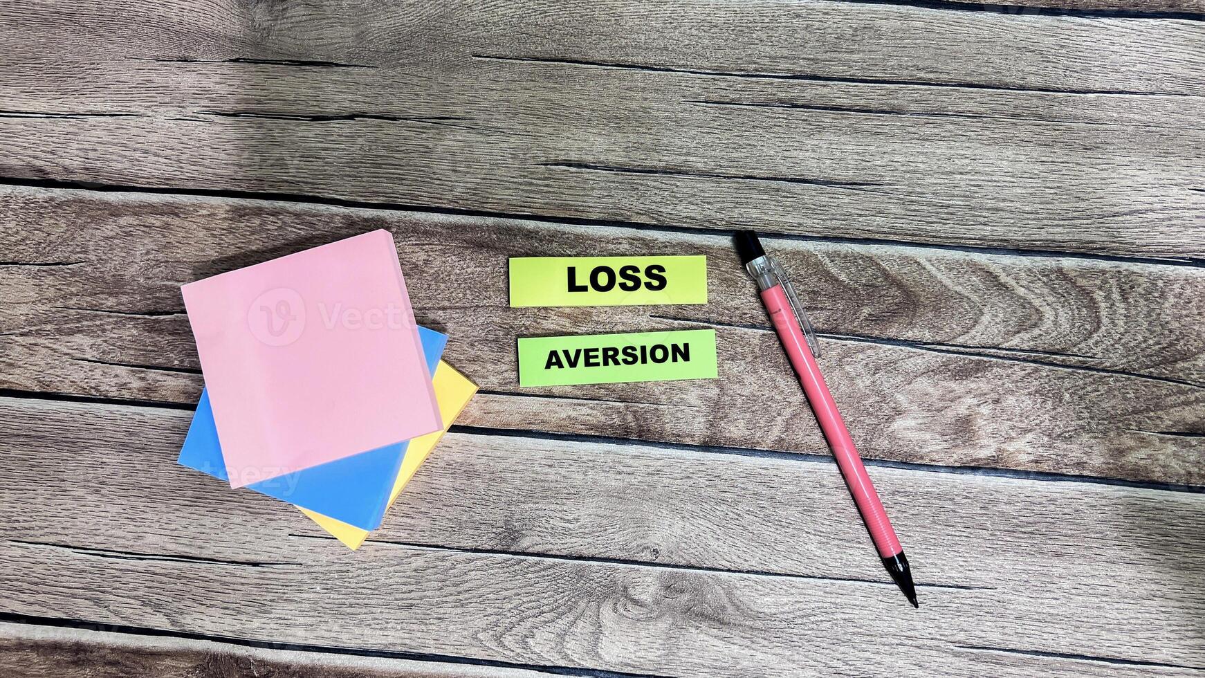 Concept of Loss Aversion write on sticky notes isolated on Wooden Table. photo