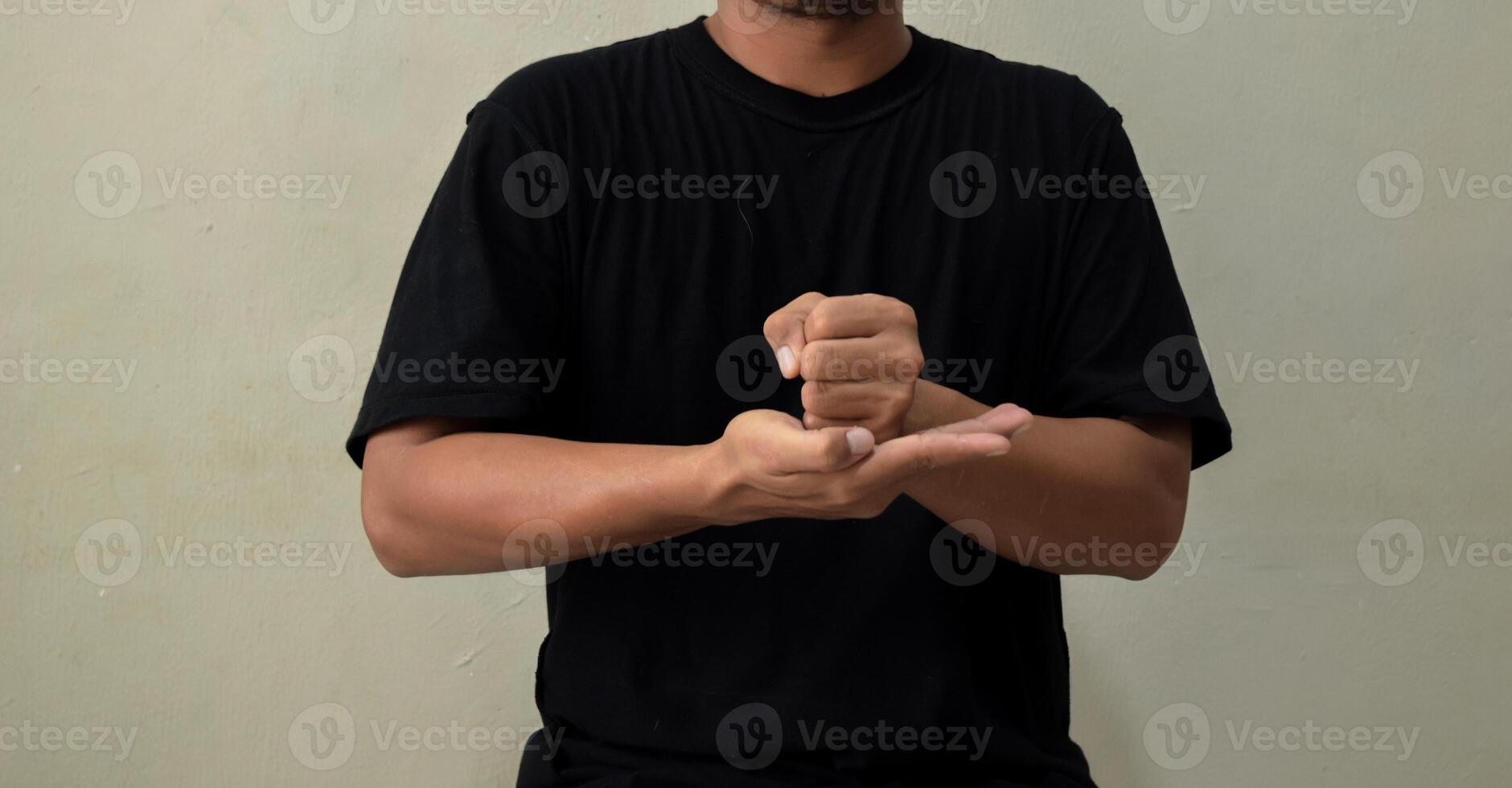 Young man showing word CRUCIFY in sign language on gray background photo