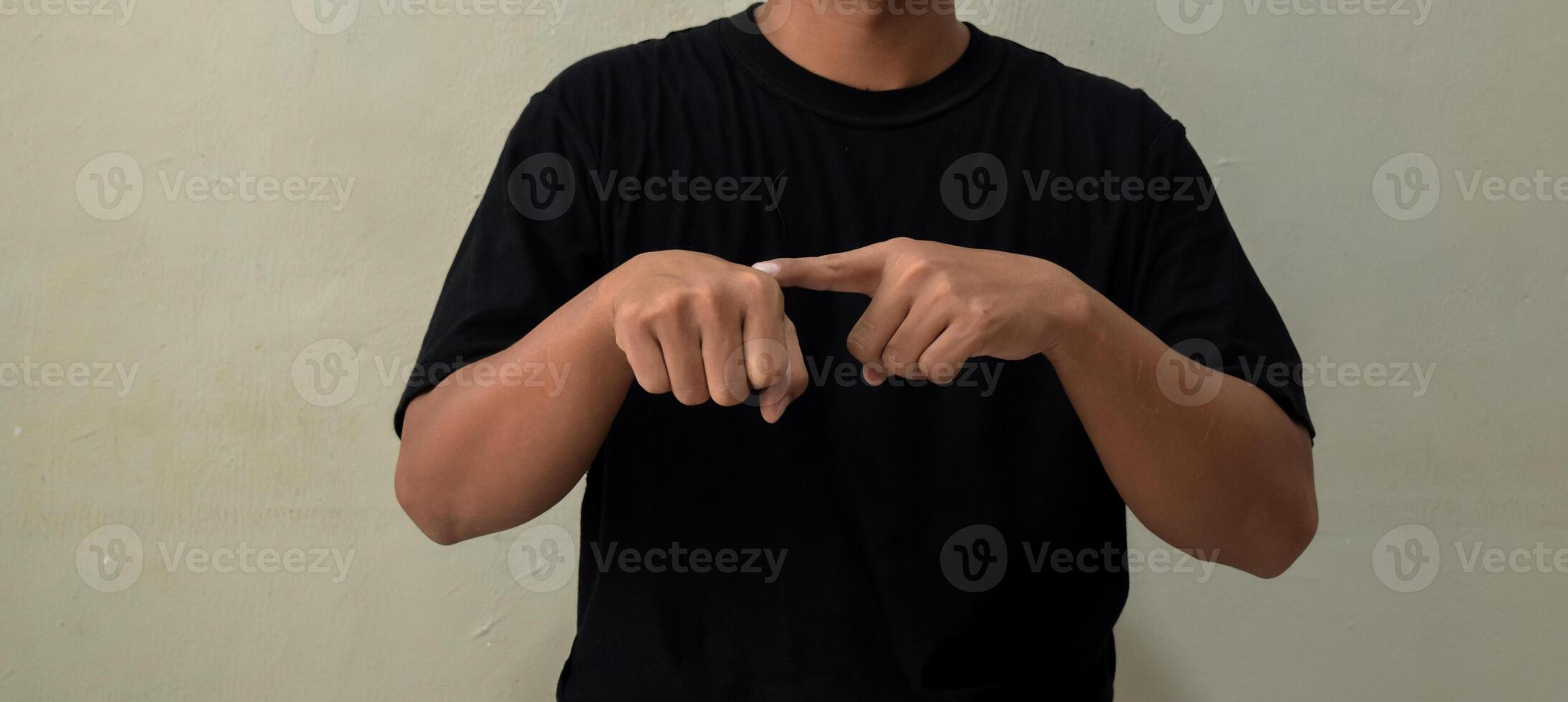 Young man showing word TIME in sign language on gray background photo