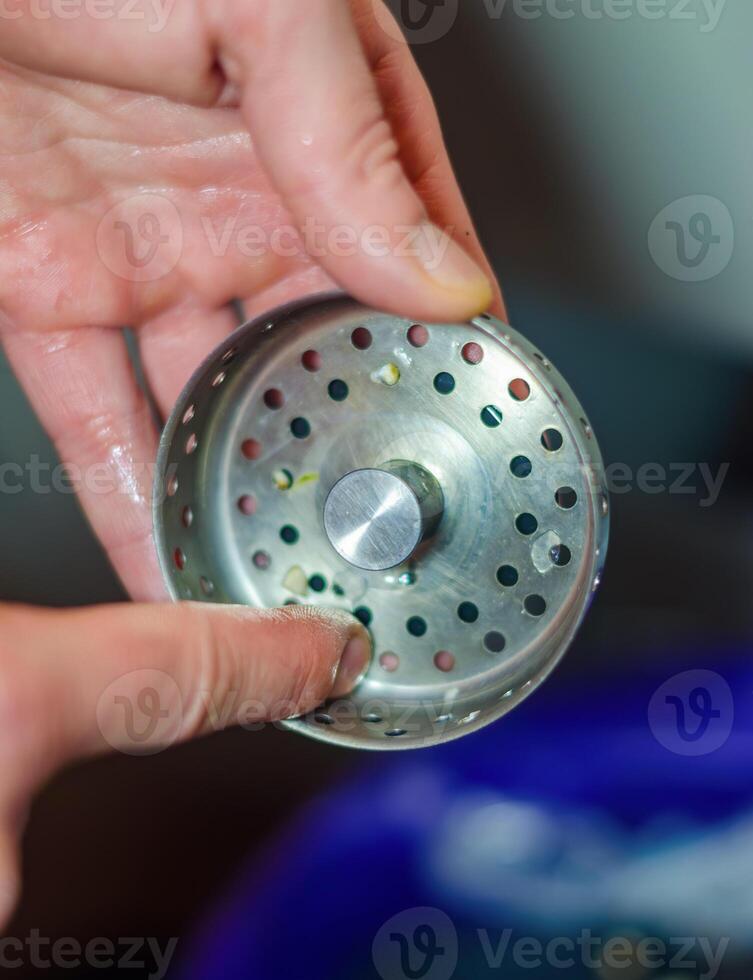 Close-up of a person holding a dirty sink strainer with food debris. High quality photo