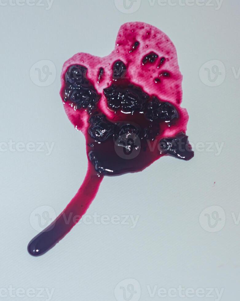 spill of dark red jam, in shape of heart, with long dripping trail on white background . High quality photo