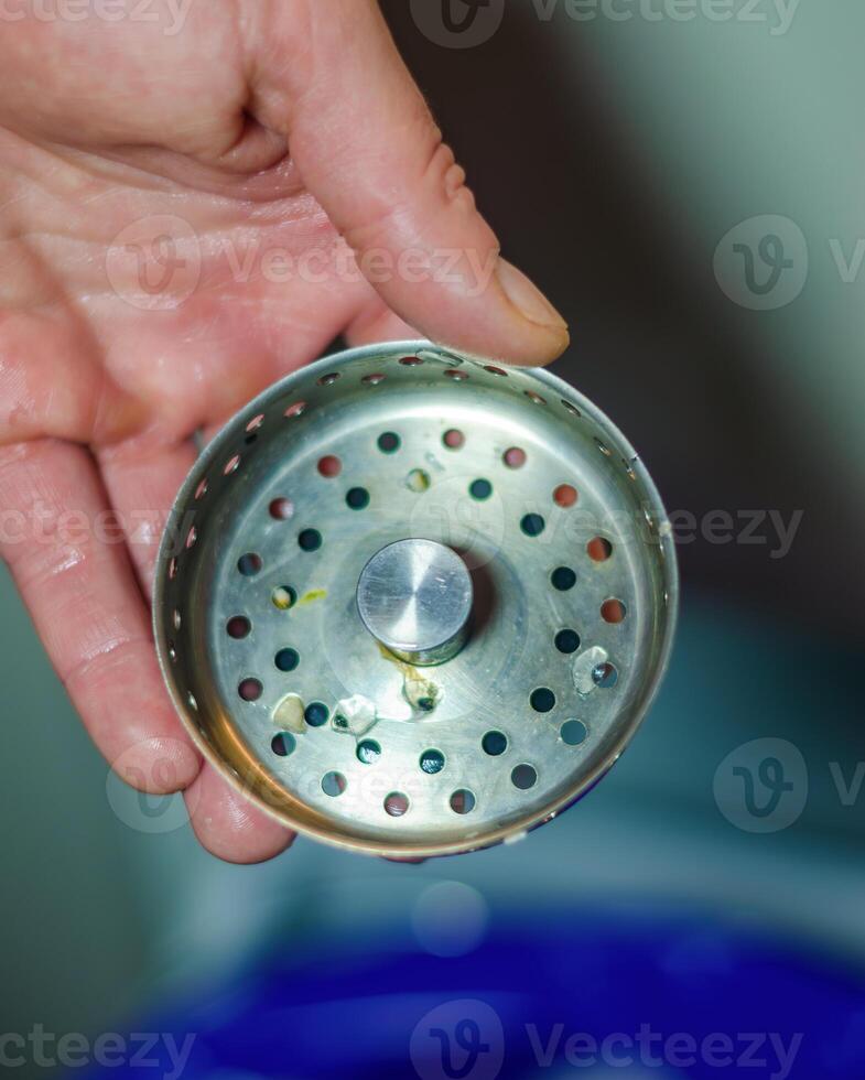 Hand holding a sink strainer full of food debris. High quality photo