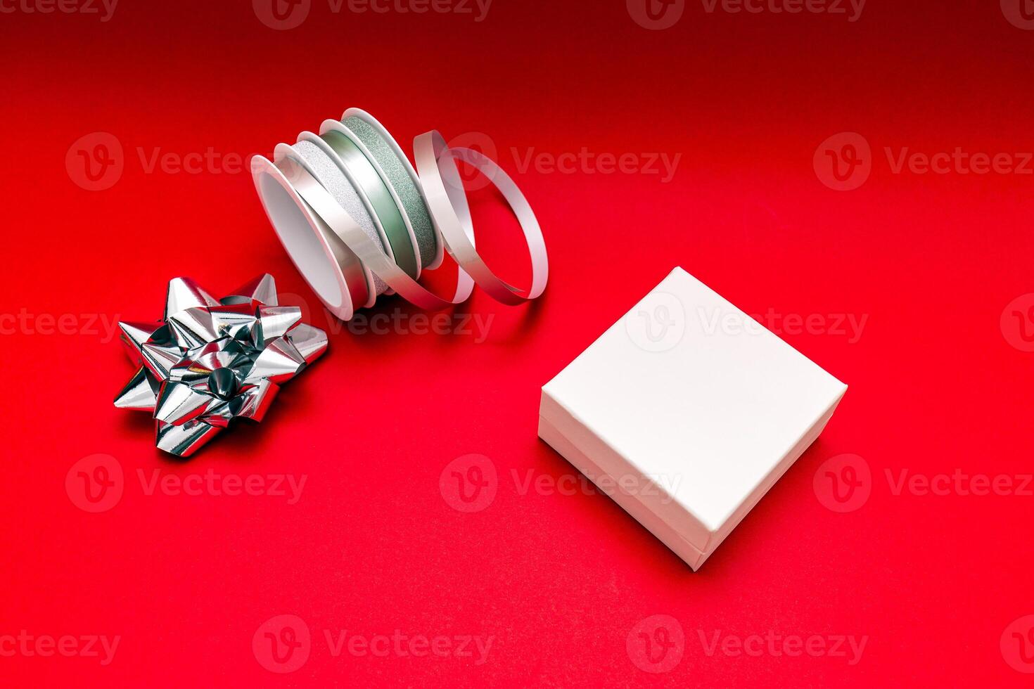 a white box with a bow and ribbon on a red background photo