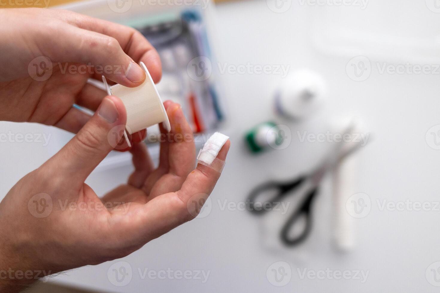 concept of first aid for cuts and injuries.a person is using a piece of tape photo
