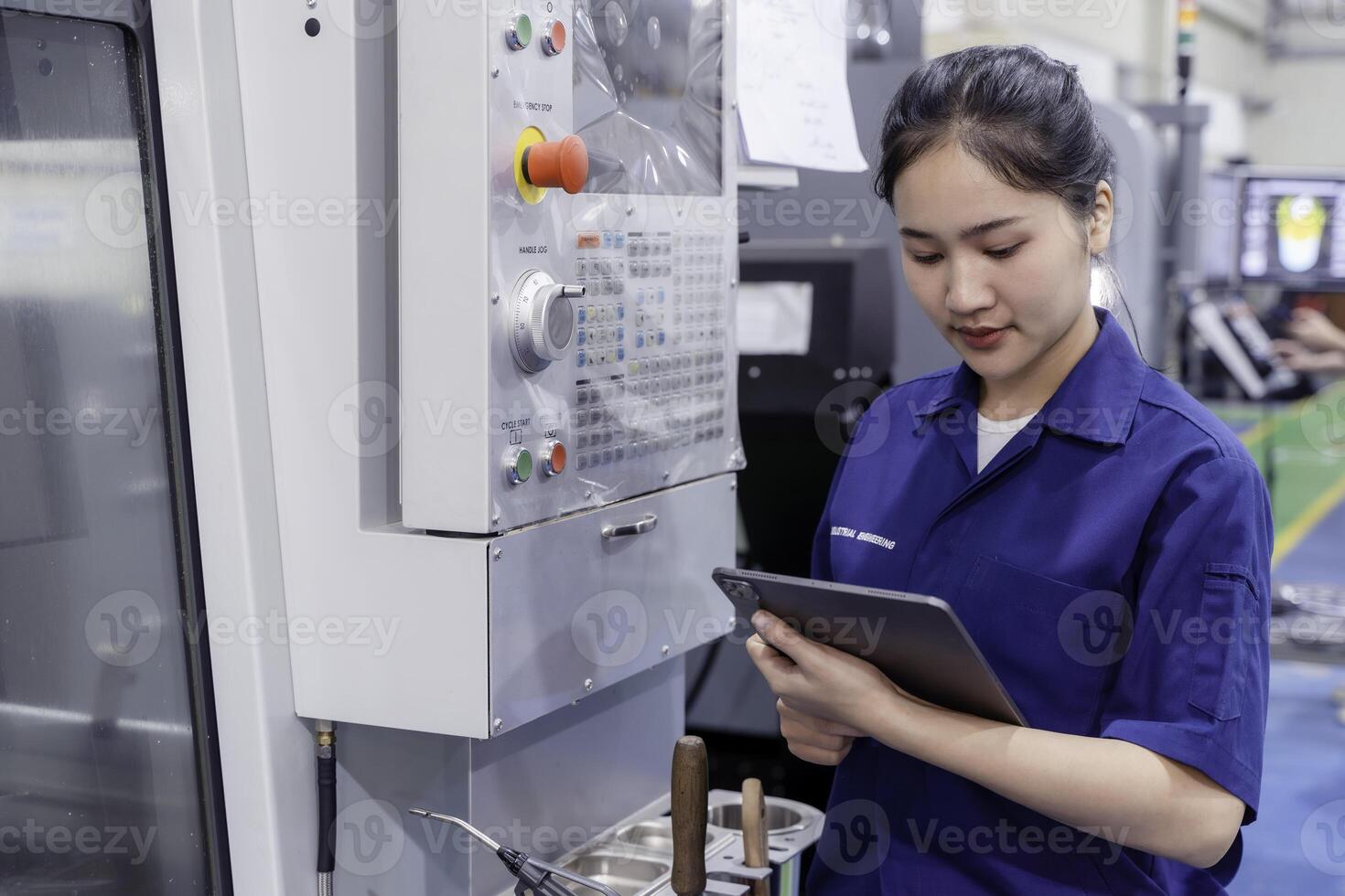 Asian woman industrial engineer wearing uniform looking and check of work on tablet with automated machinery in industrial workshop. photo