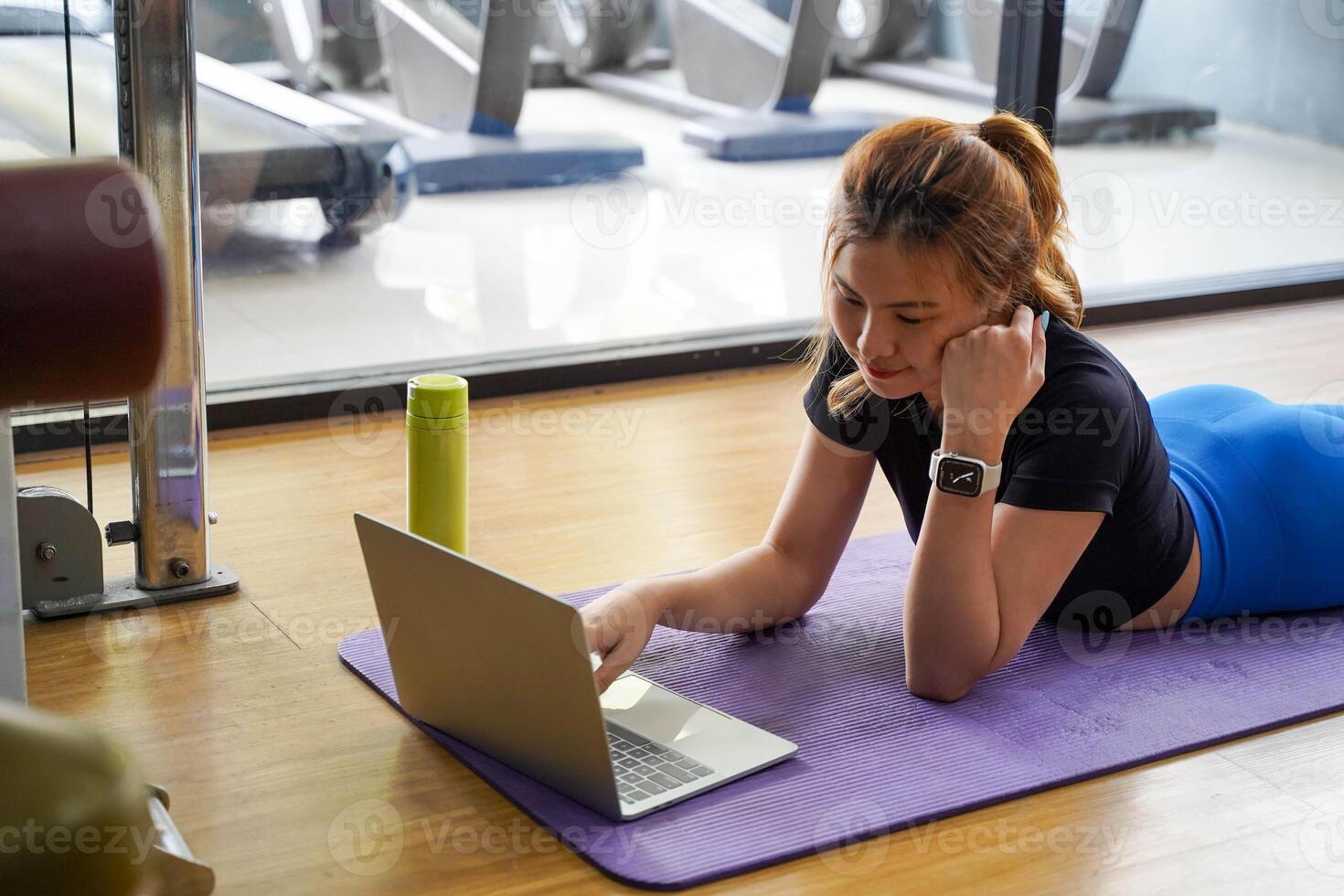 Closeup Asian young female relaxing with play laptop after workout and Yoga in the fitness center photo