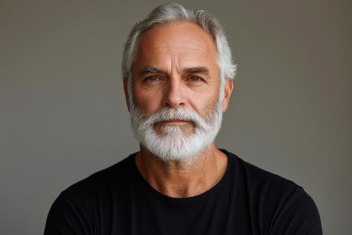 Mature man with gray hair and beard showing a thoughtful expression indoors photo