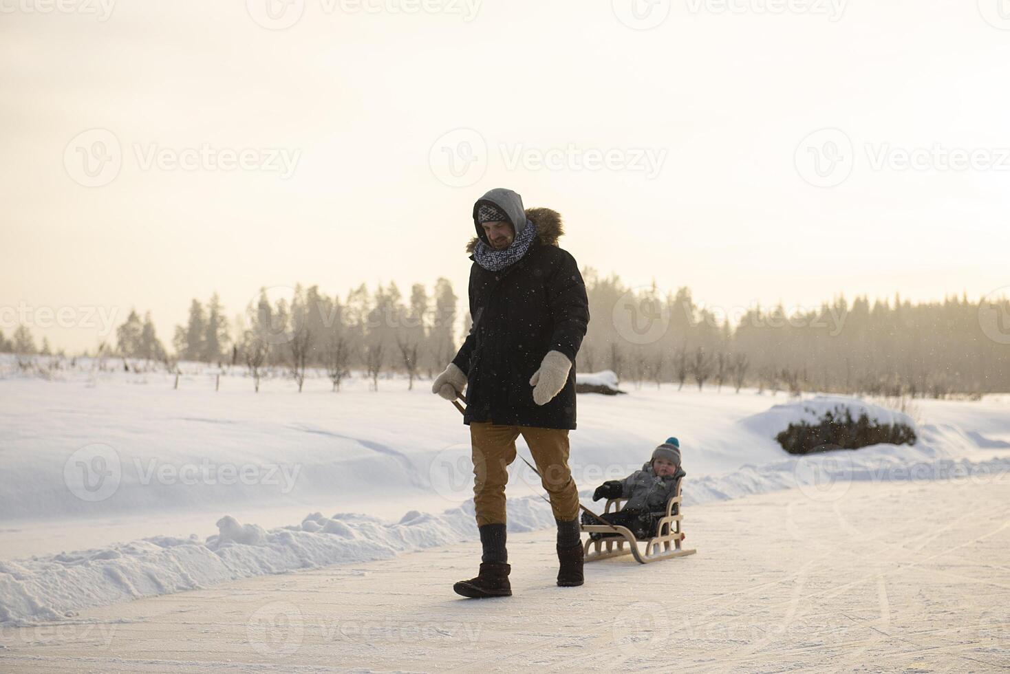 A father is sledding his child across the ice of a frozen pond on a sunny winter day. photo