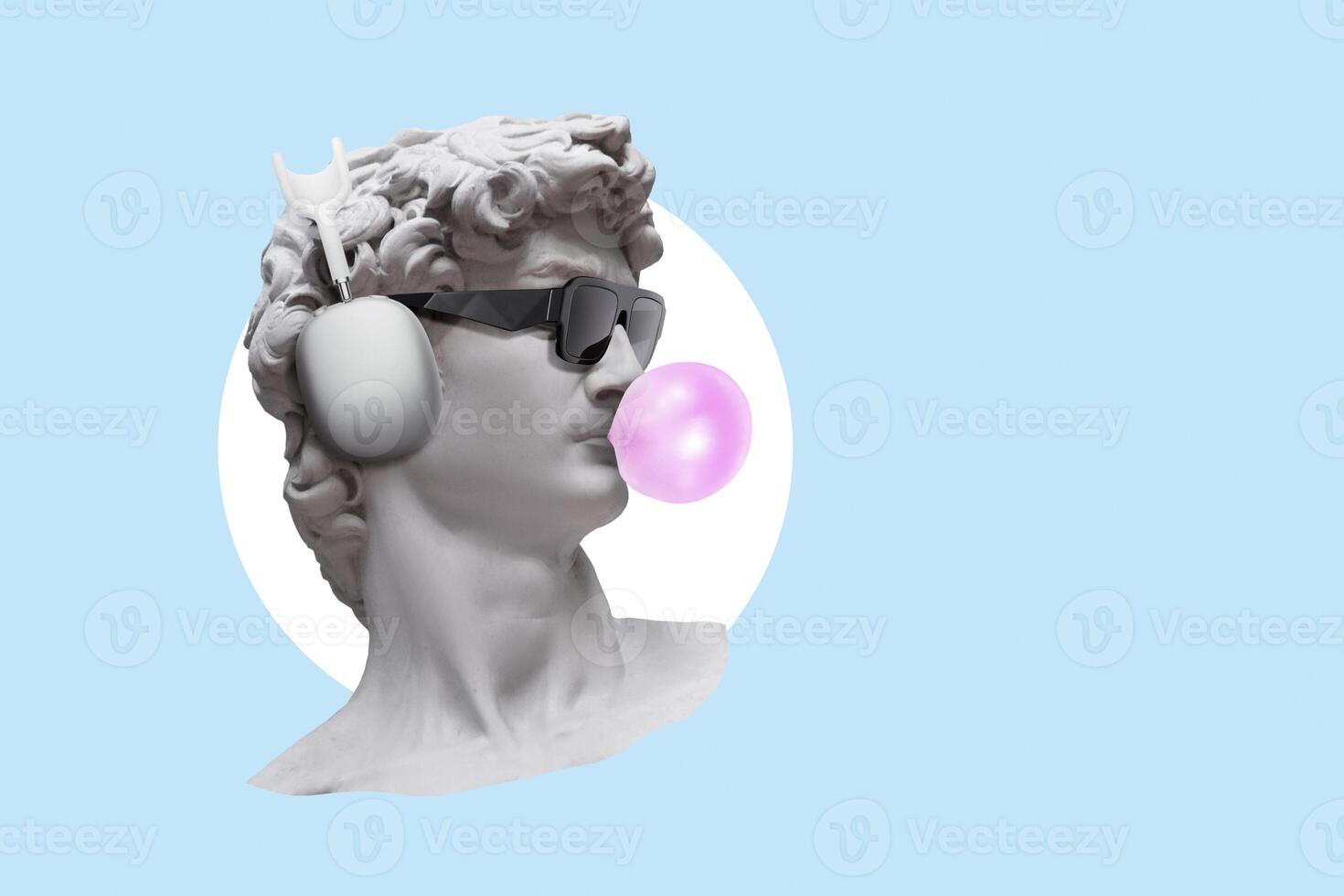 Creative hipster statue with bubblegum bubble, fashionable glasses and headphones on blue background. Earphone. Gypsum statue of David's head, concept. Neoclassic photo