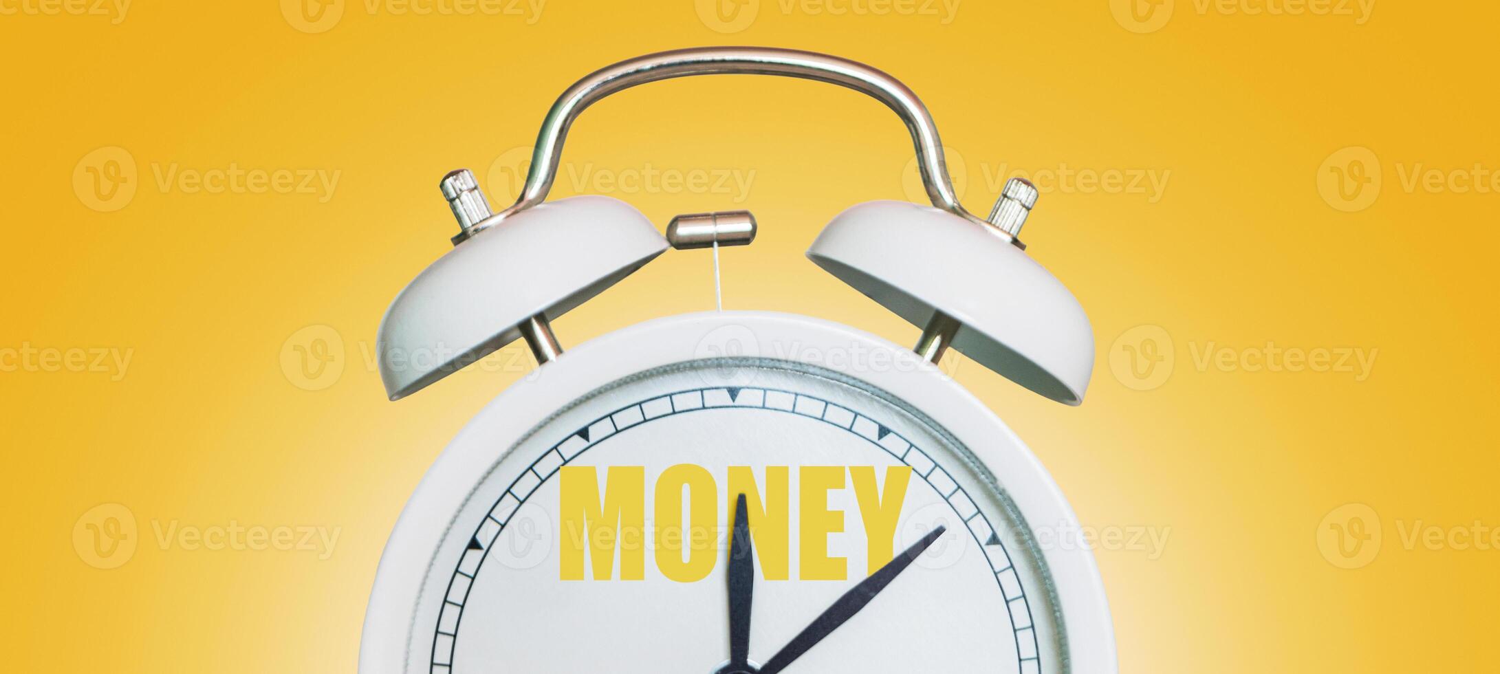Time for money. White vintage clock pointing to Money on a yellow background photo
