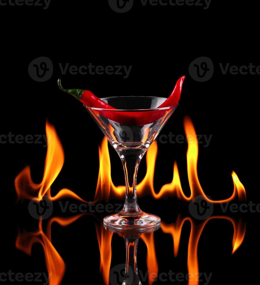 Hot chili pepper in a martini glass with a fire on a black background photo