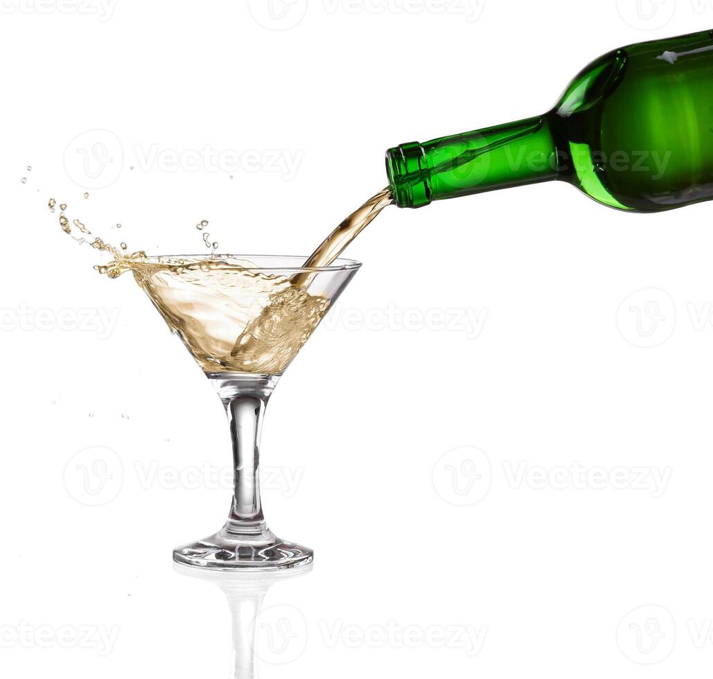 White wine pouring from the bottle intro the glass on white background photo