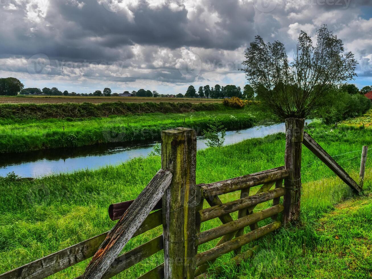 A wooden fence and a river in a field photo