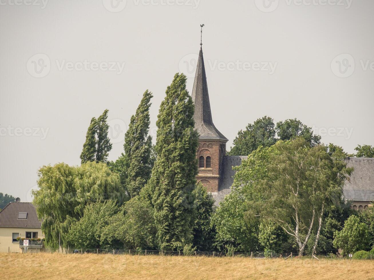 A church with a steeple and trees in the background at bislich photo
