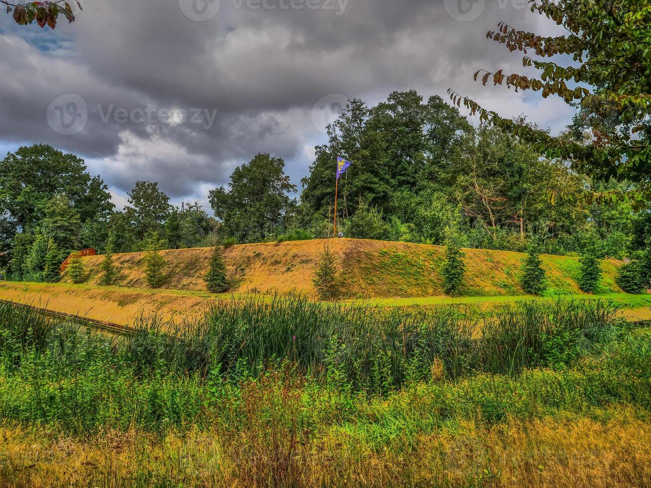 A grassy field with trees and a hill photo