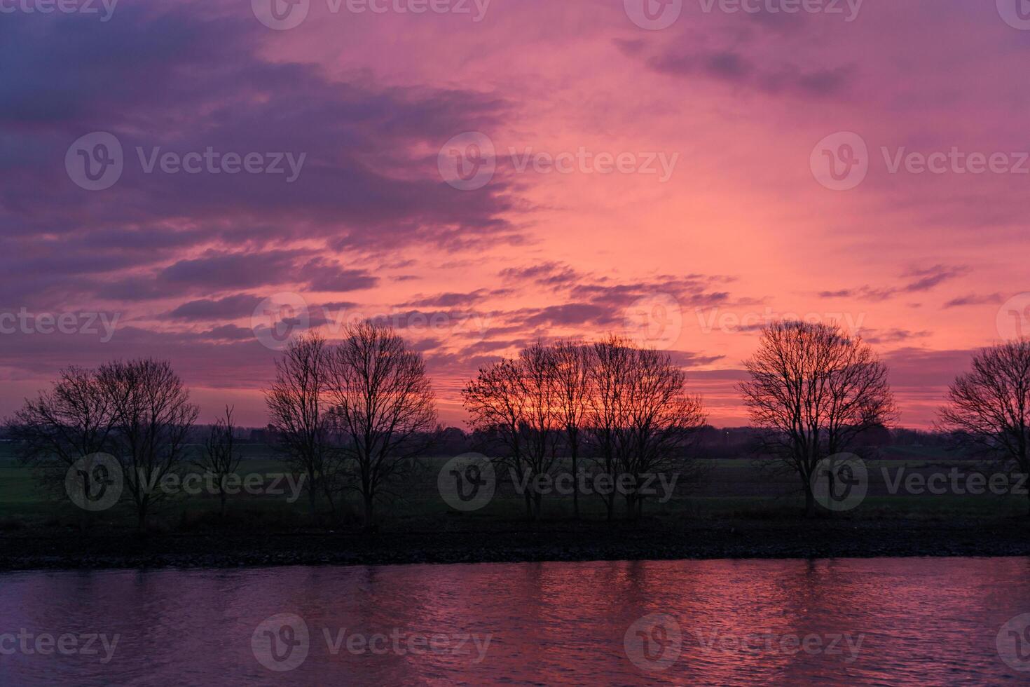 A sunset over a river with trees in the foreground photo