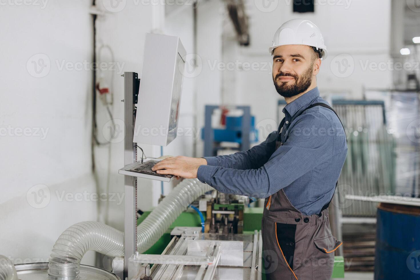 Factory worker operating industrial computer controlled machinery for pvc windows and doors production photo