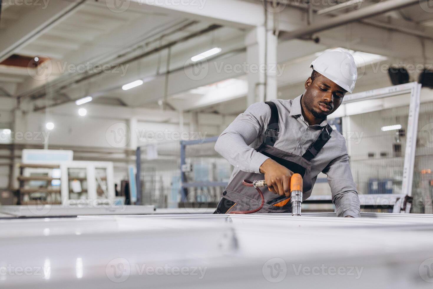 Factory worker assembling aluminum window frames using pneumatic screwdriver photo