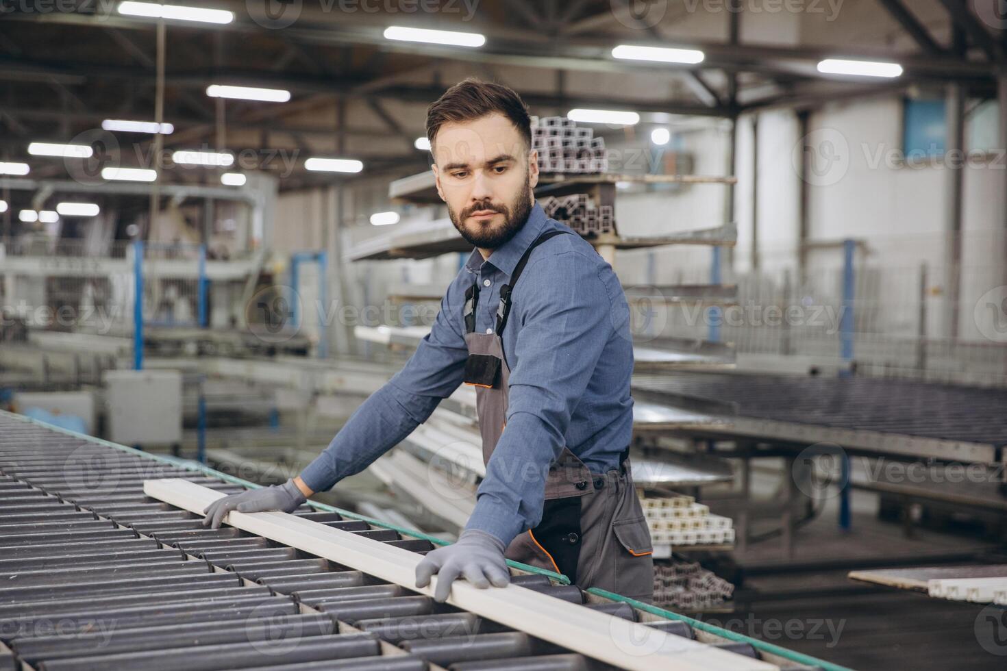Factory worker placing wooden plank on assembly line for PVC windows and doors production photo