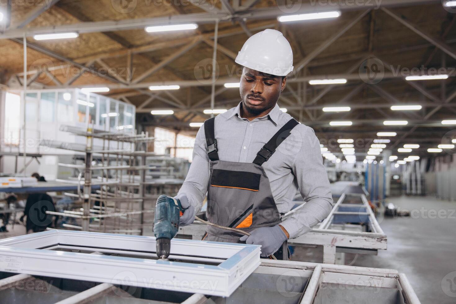 Factory worker assembling pvc window frame using electric screwdriver photo