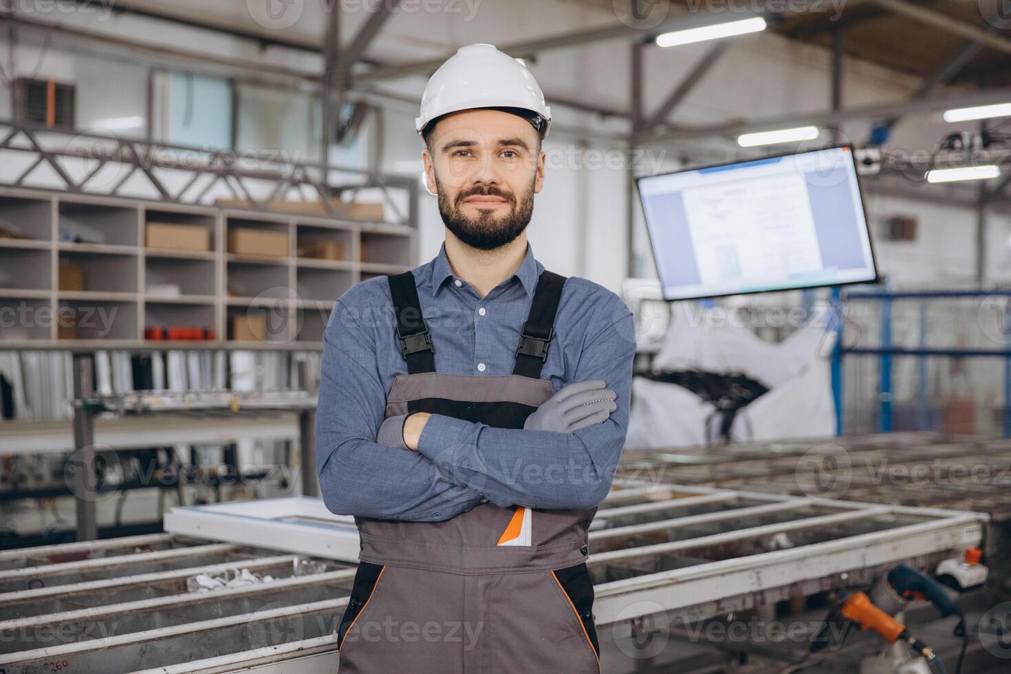 Factory worker posing with crossed arms in windows and doors production line photo