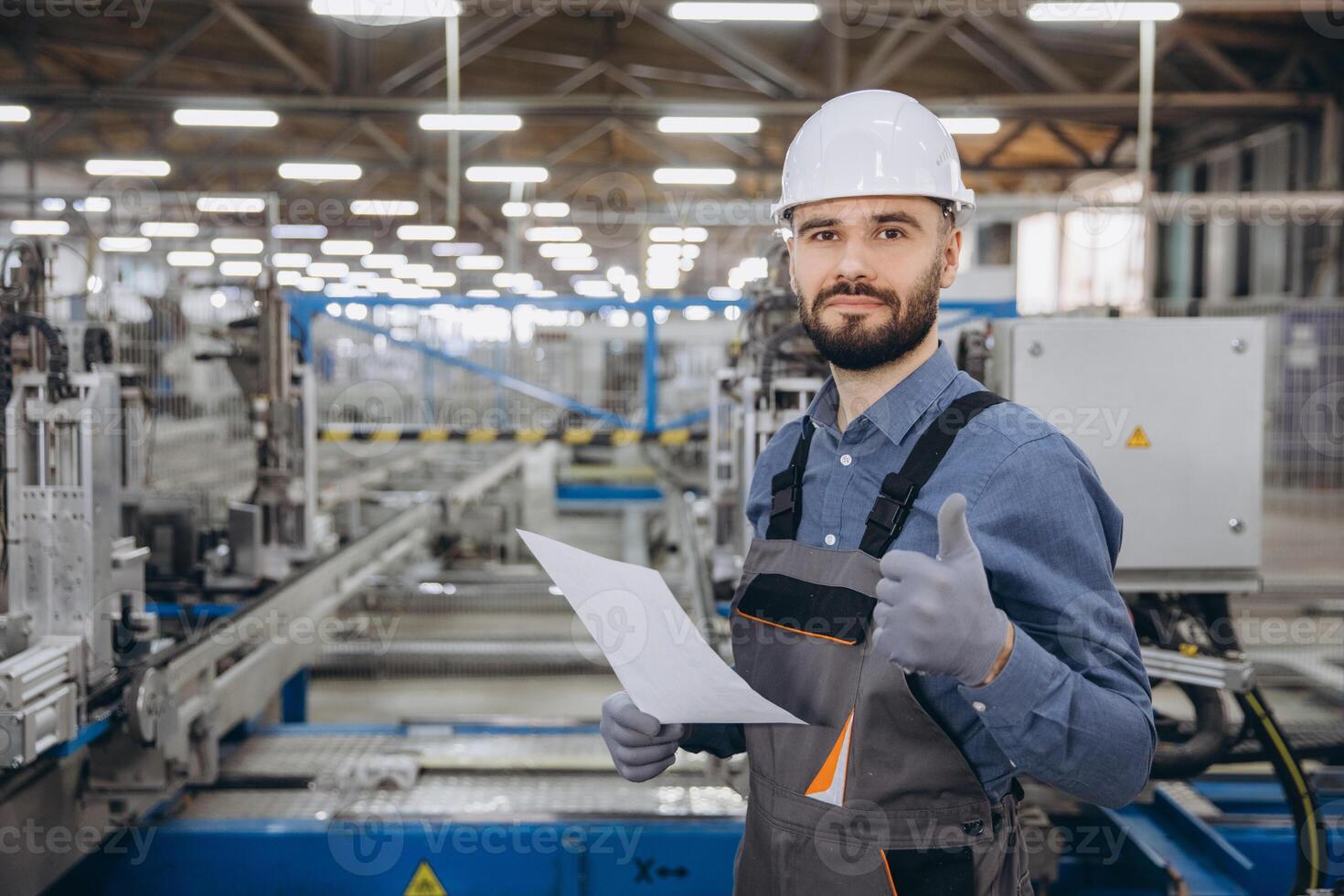 Factory worker showing thumbs up while holding documents in metalwork production line photo