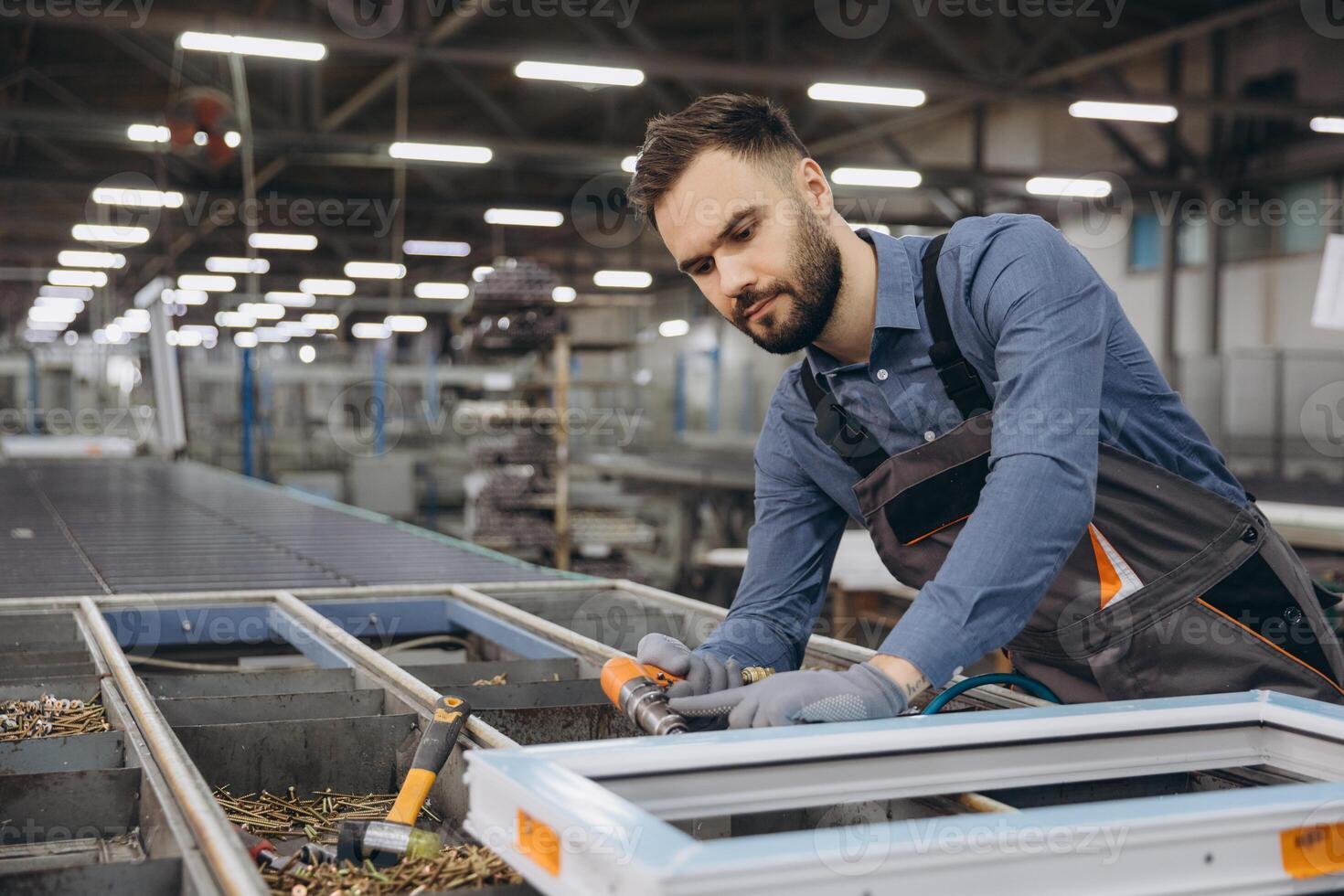 Factory worker assembling aluminum and PVC window frame on production line photo