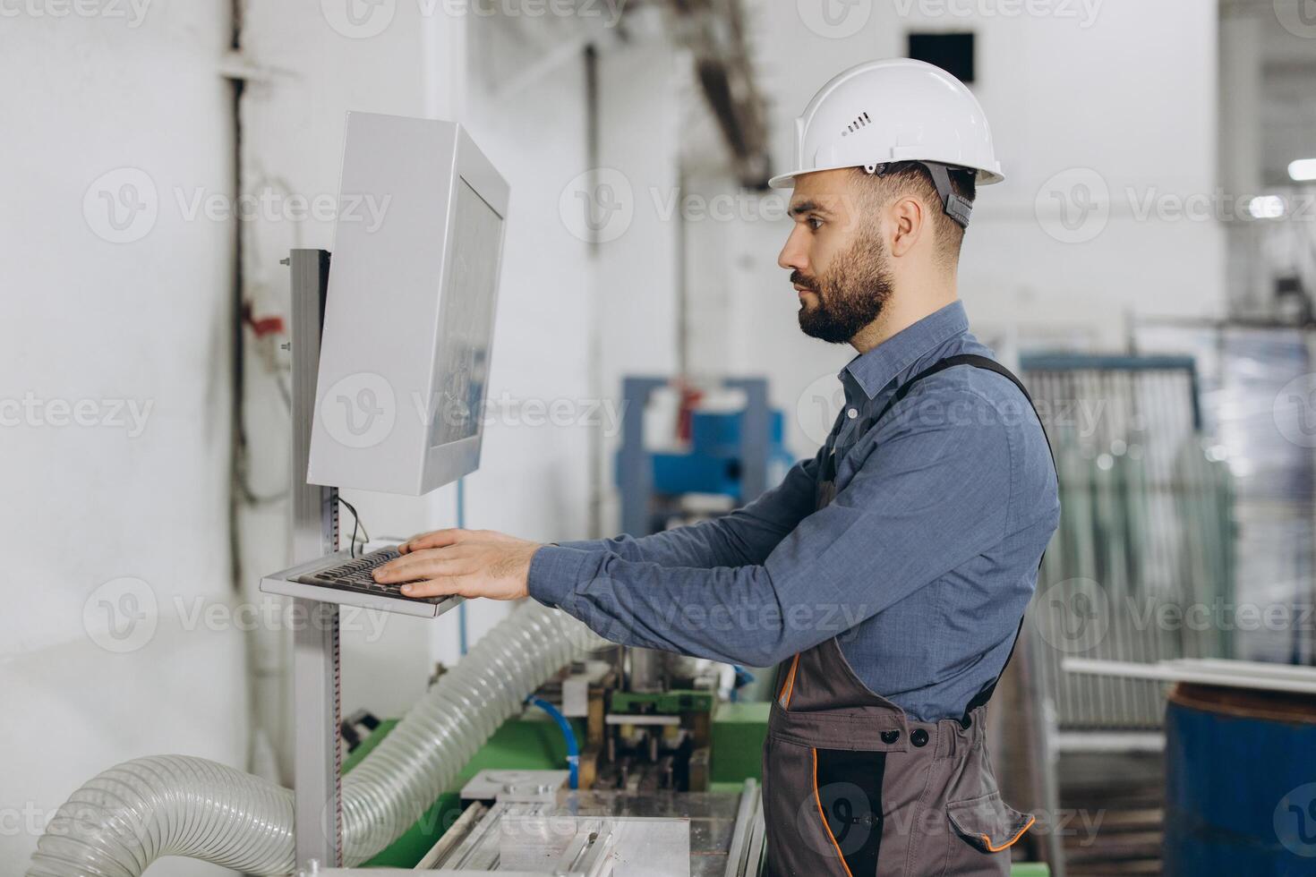 Factory worker operating computer controlled machinery for aluminum and pvc windows and doors production photo
