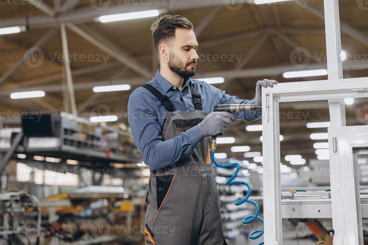 Factory worker assembling pvc window frame using pneumatic screwdriver photo