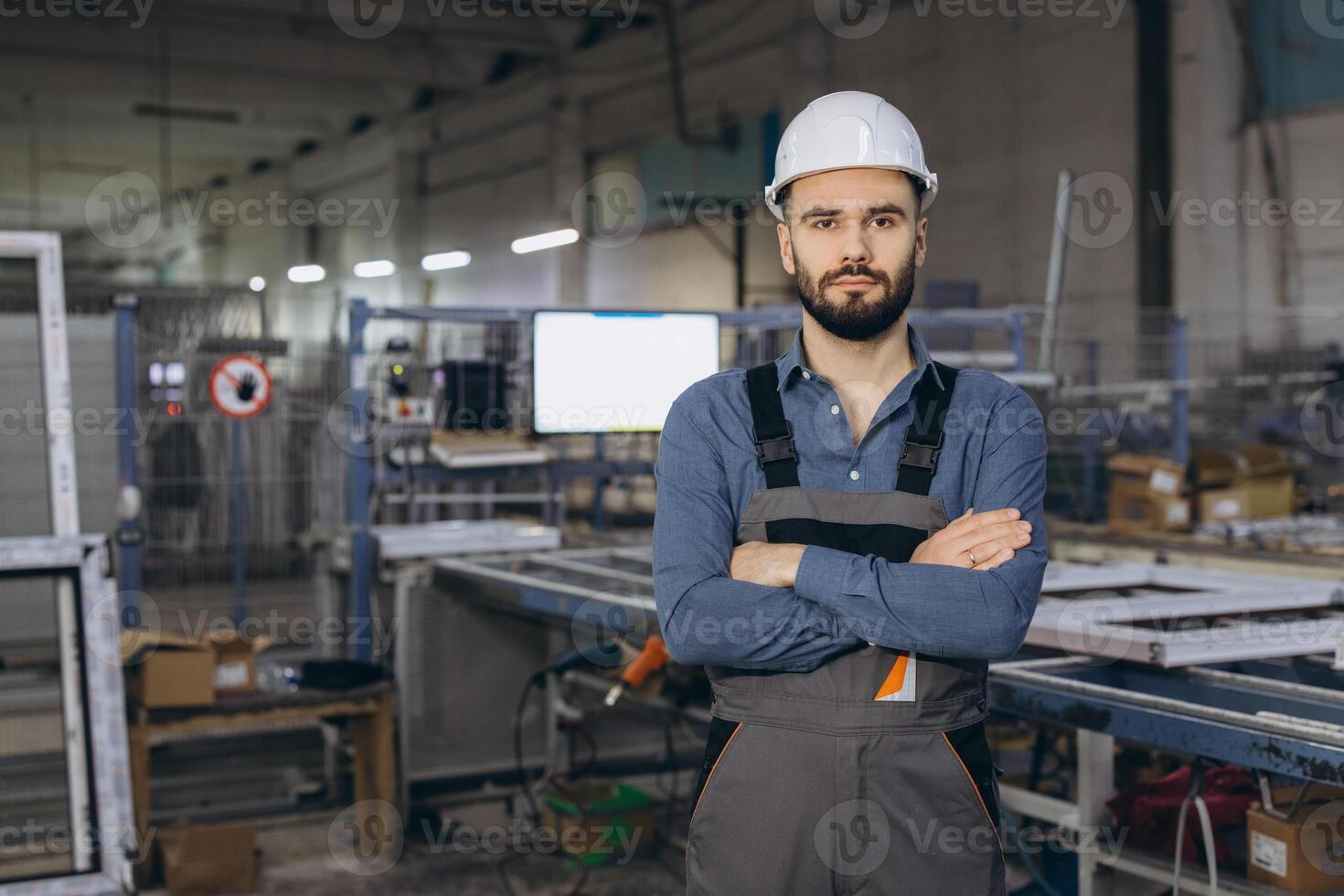 Factory worker posing with crossed arms in window and door production line photo
