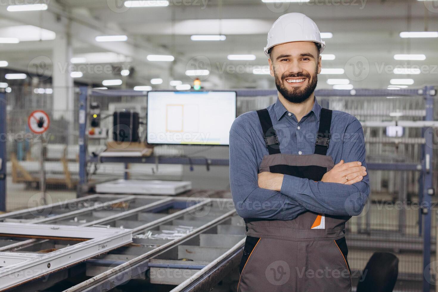 Smiling factory worker posing with arms crossed in PVC windows and doors production line photo