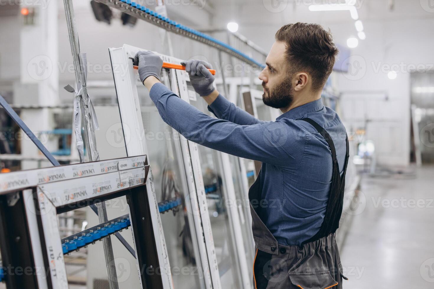 Factory worker measuring PVC window frame in production line photo