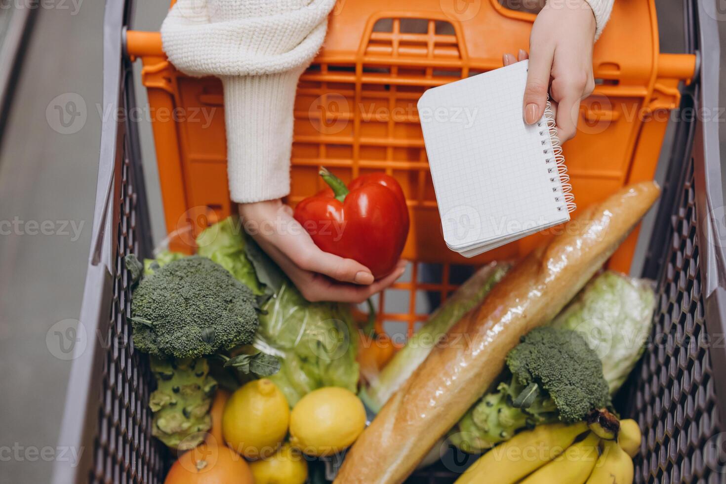 Woman grocery shopping holding red bell pepper and shopping list photo