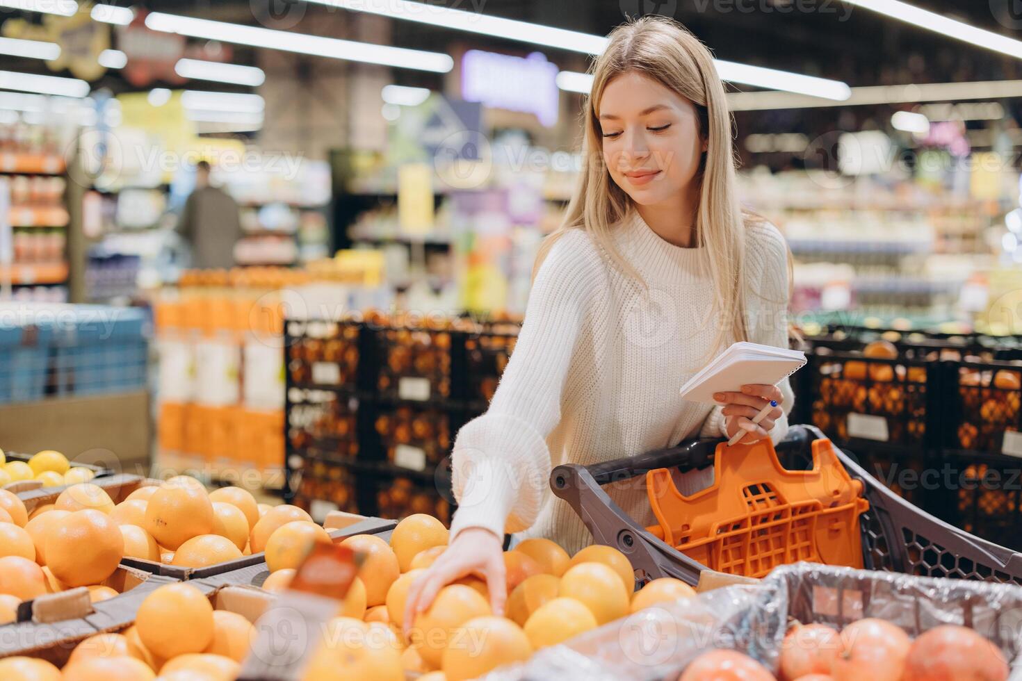 Customer choosing grapefruits in supermarket holding shopping list photo