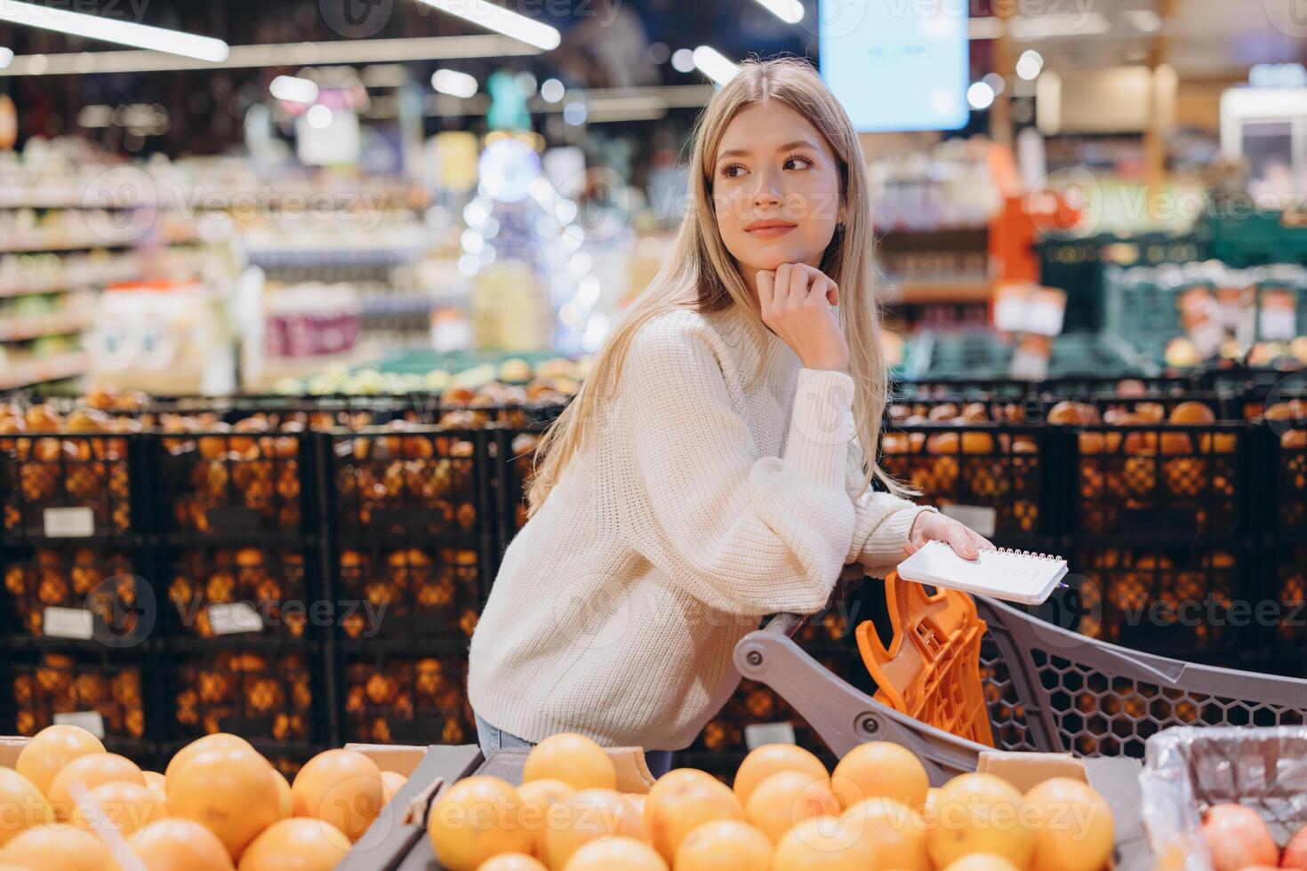 Customer choosing grapefruits in supermarket holding shopping list photo