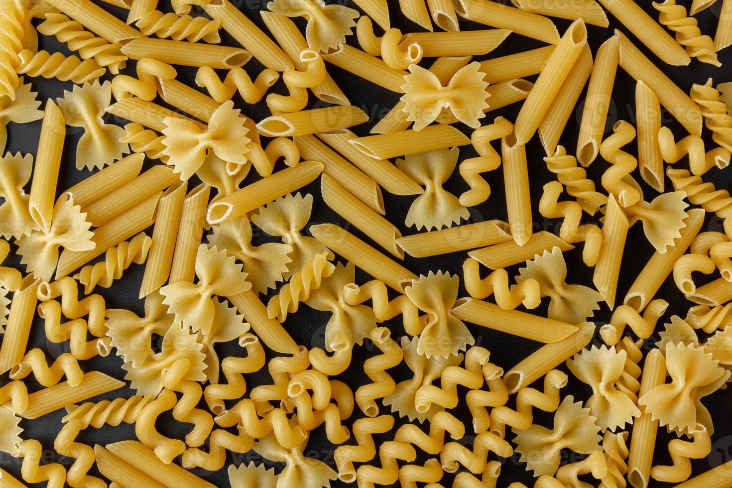Different kinds of raw pasta texture on black background. photo