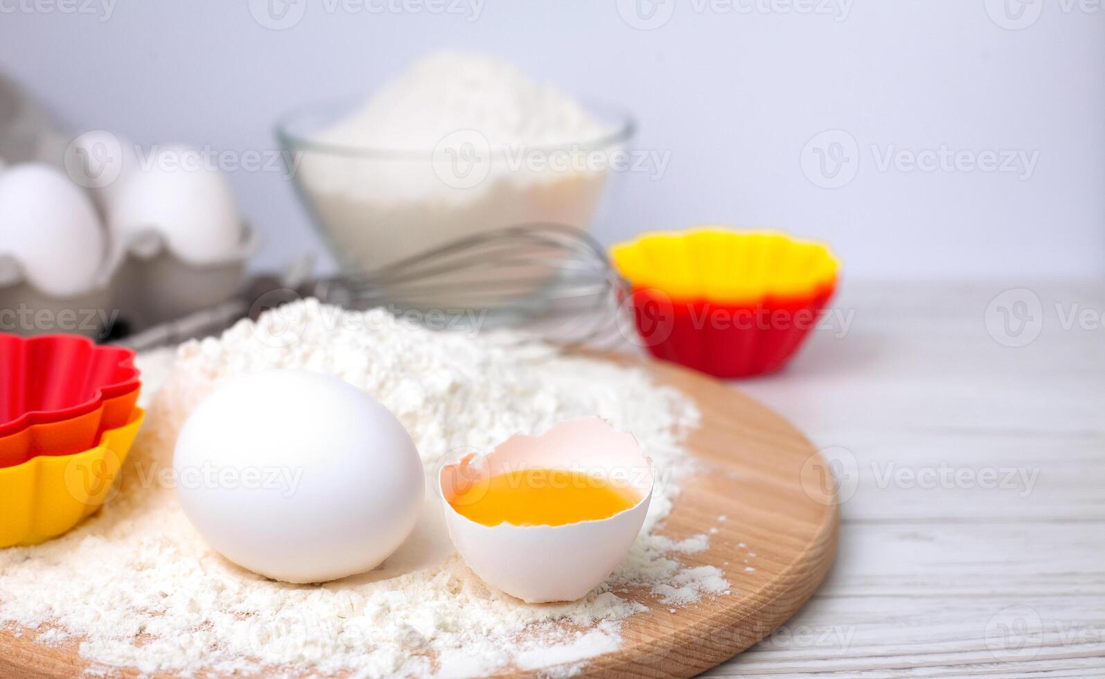 Ingredients for baking cupcakes for the holiday. Flour, eggs and multicolored silicone form on a table. Close-up. Copy space. photo
