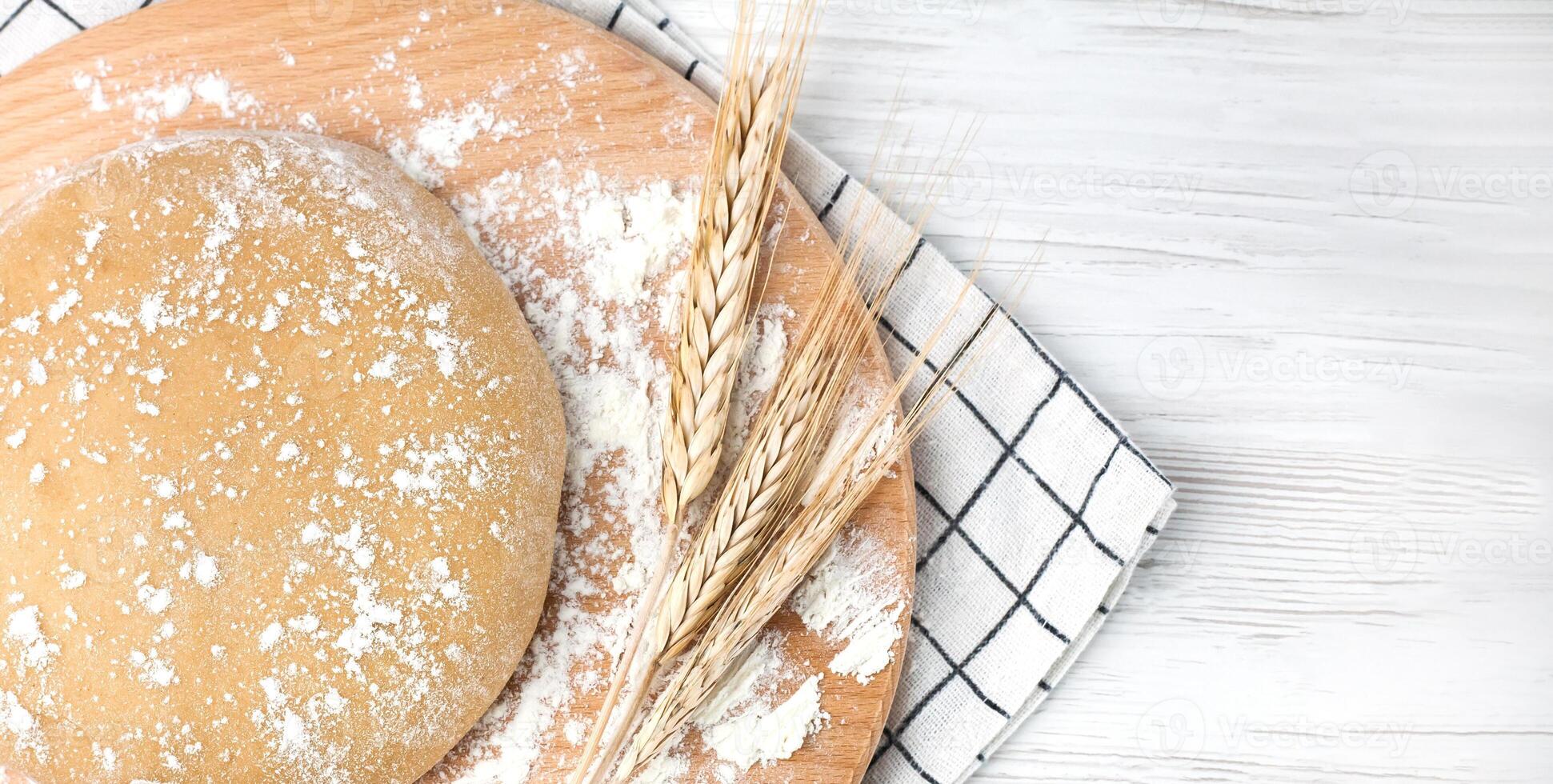 Fresh dough on a wooden board on the table. Baking bread or biscuits. Close-up.Copy space. Top view. photo