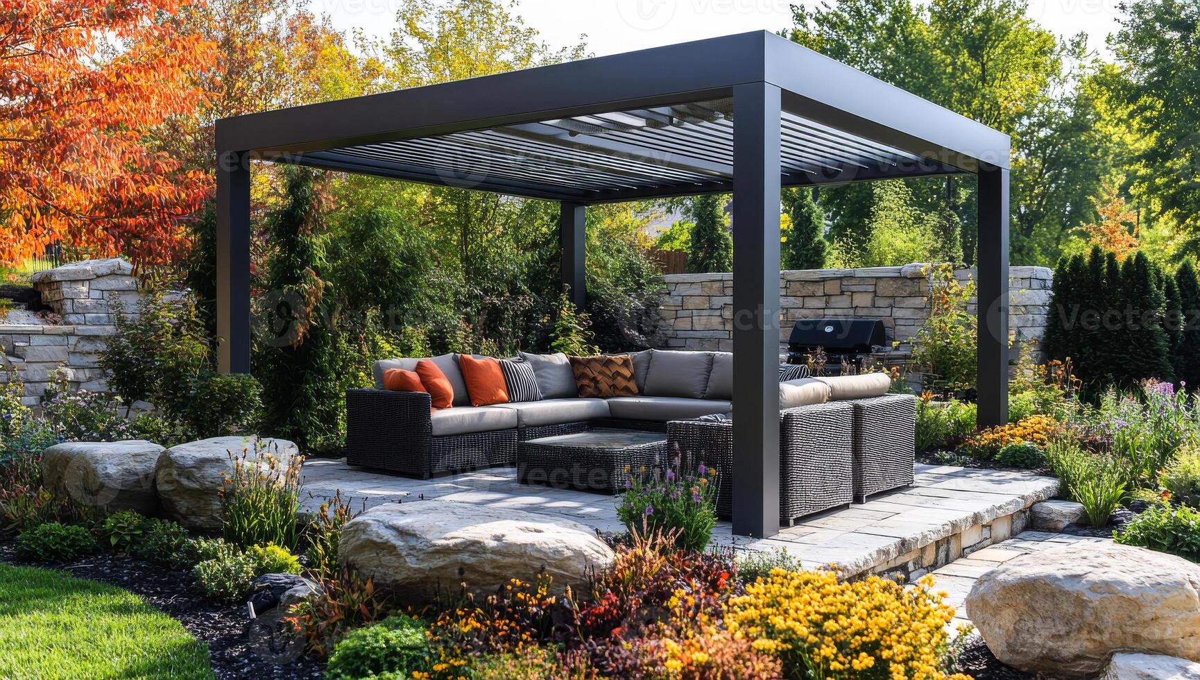 A large patio with a black gazebo and a stone wall. The patio is filled with comfortable furniture and colorful flowers photo