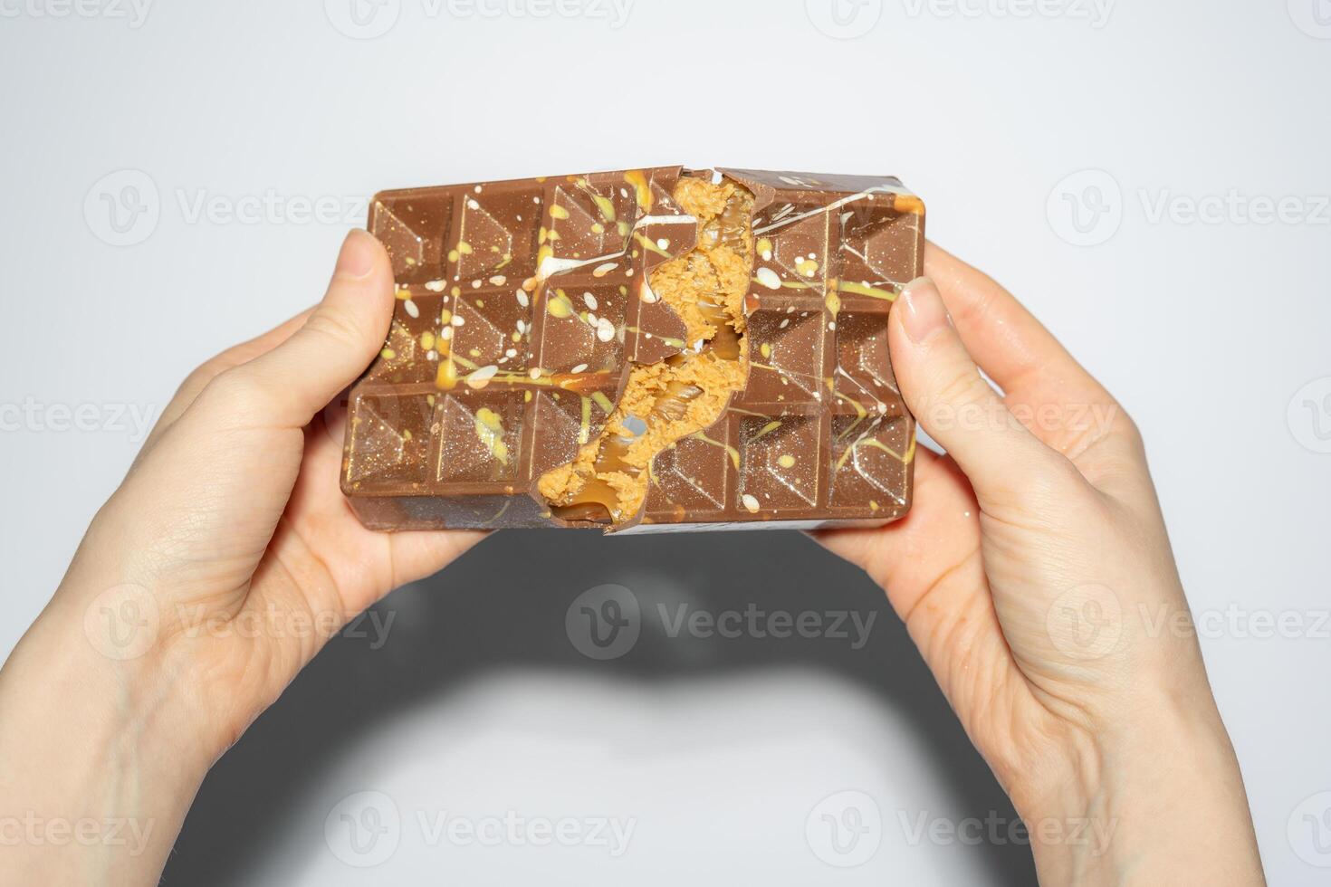 Close up of famous Dubai chocolate with peanut butter, caramel and kadaif broken in woman's hands. Confectionery handmade sweets, chocolatier. photo