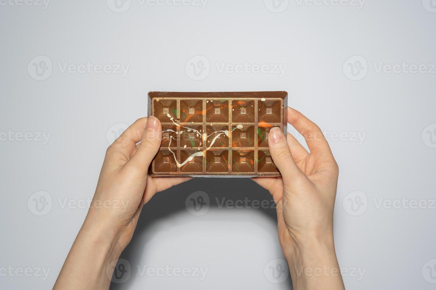 Famous Dubai chocolate with pistachio, tahini and kadaif in woman's hands on white background. Confectionery handmade sweets, chocolatier photo